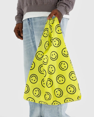ein Mann mit einer wiederverwendbaren Einkaufstasche - gelb mit schwarzen Smileys