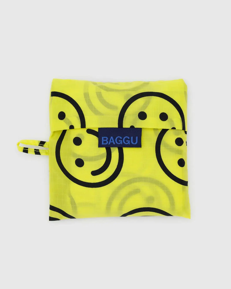 Eine wiederverwendbare Einkaufstasche in ihrer kleinen Tüte - gelb mit schwarzen Smileys