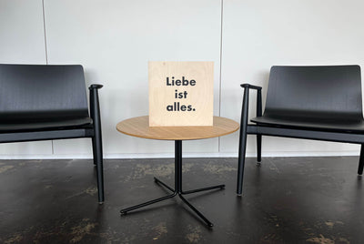 Ein Holzschild im Büro, schwarze Buchstaben "Liebe ist alles" steht darauf