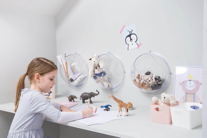 Mädchen im Kinderzimmer sitzt am Tisch und malt, 3 Wandkugeln aus Kunststoff hängen an der Wand