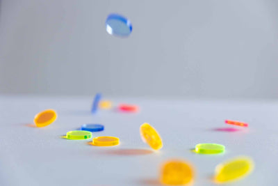 Neon-Acryl-Konfetti, das auf einen weißen Tisch fällt