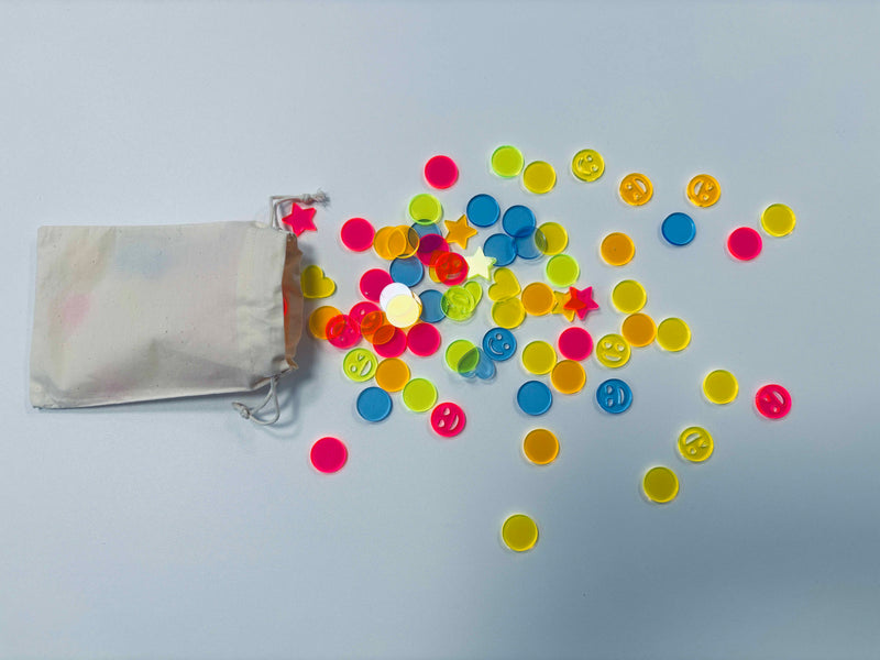 neonfarbenes Acryl-Konfetti auf einem weißen Tisch, mehr in einem wiederverwendbaren Baumwollsäckchen