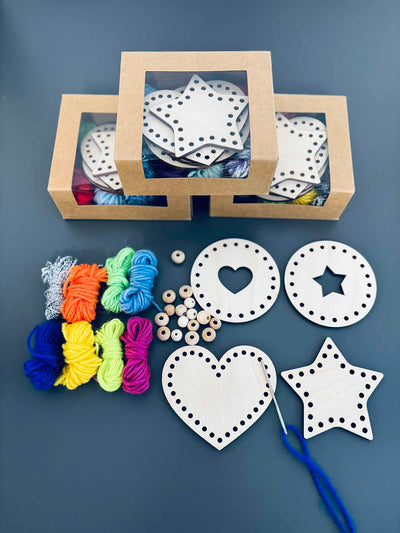 Ein Flatlay eines Stickerei-Bastelsets - Holzformen, Garn, eine Nadel, Holzperlen