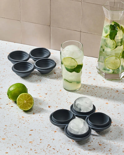 Ein wiederverwendbarer Kugel-Eiswürfelbehälter auf einer Küchenarbeitsplatte mit einem Krug eines erfrischenden Limonendrinks