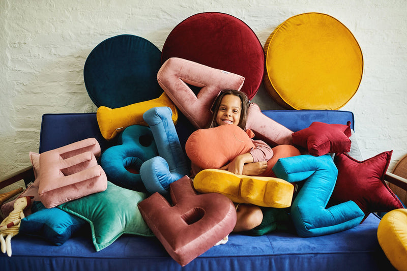Mädchen mit bunten Samtkissen lächelnd auf dem Couch
