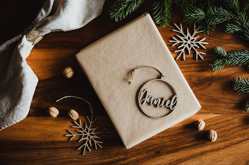Weihnachtskugel aus Holz mit Namen Daniel liegend auf einem Weihnachtsgeschenk