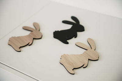 Drei Osterhasen aus Holz und Acryl liegend auf einem weißen TIsch