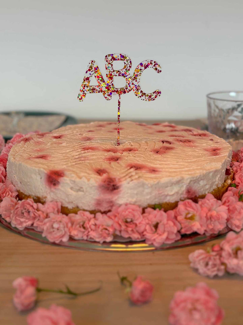 ABC pink gold Glitzer Acryl Caketopper auf einem pinken Kuchen mit Blumen auf dem Tisch