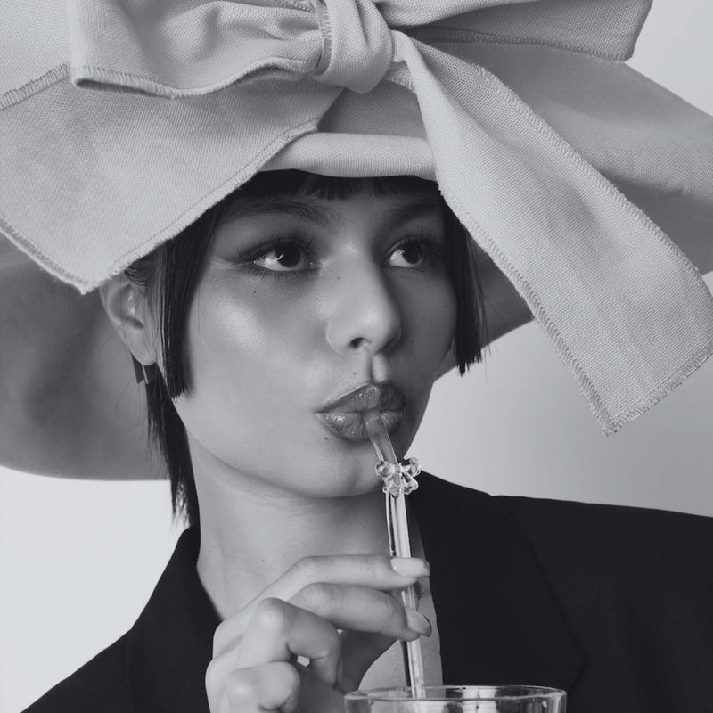 Eine Frau trinkt aus einem Glas mit einem Schleifenstrohhalm