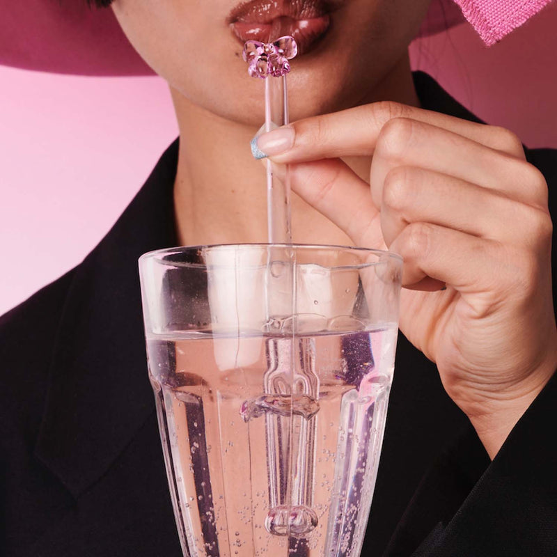 Eine Frau trinkt aus einem Glas mit einem Schleifenstrohhalm