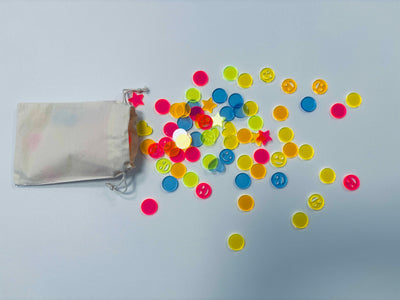 neonfarbenes Acryl-Konfetti auf einem weißen Tisch, mehr in einem wiederverwendbaren Baumwollsäckchen