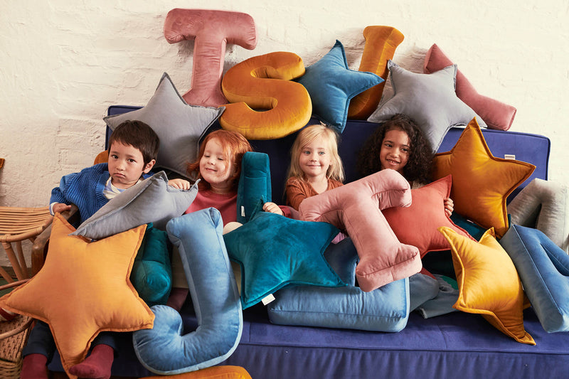 Vier Kinder auf einem Couch mit Samtkissen überall