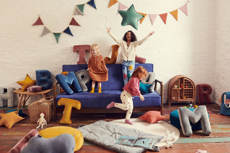 Kinder im bunten Wohnzimmer mit Couch und bunten Samtkissen