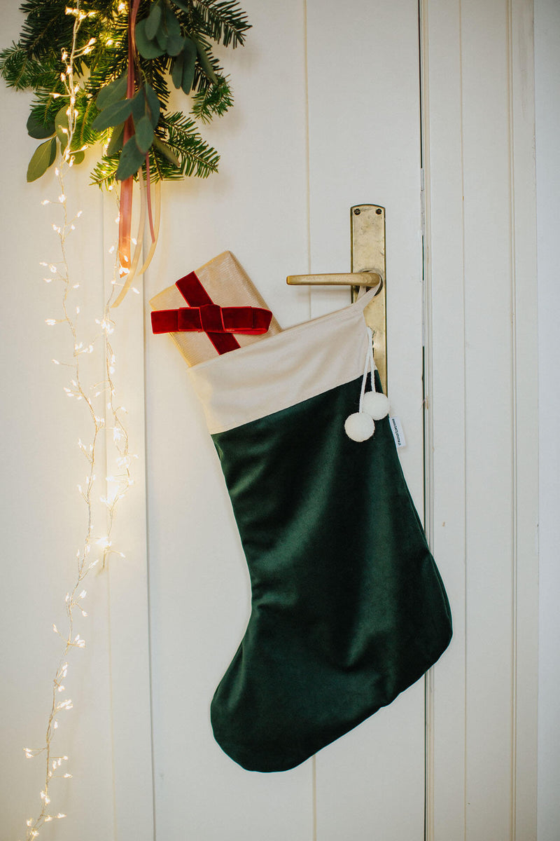 grüner Weihnachtsstrumpf aus Samt hängt an einer Tür