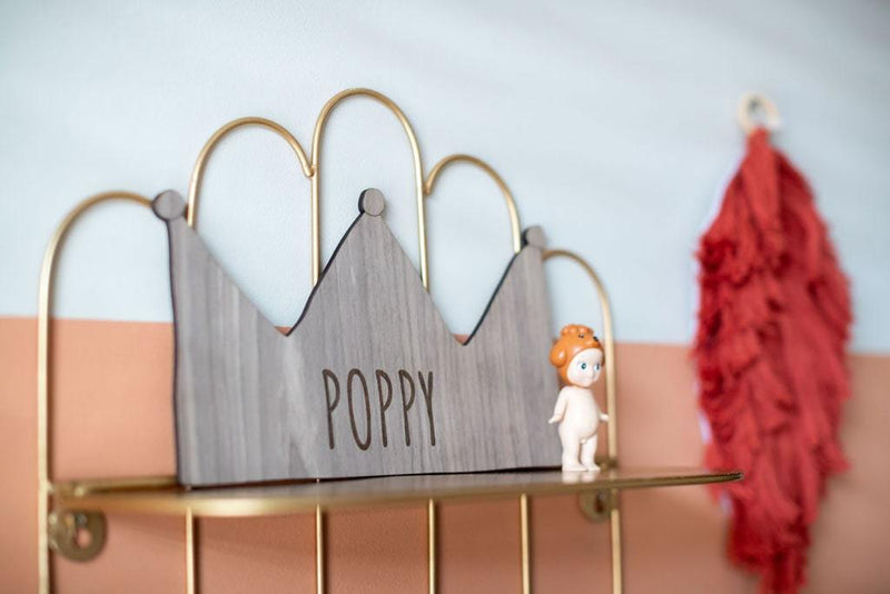 Deine Krone - personalisierte Krone mit den Namen Poppy, an einem goldenen Regal mit kleiner Puppe