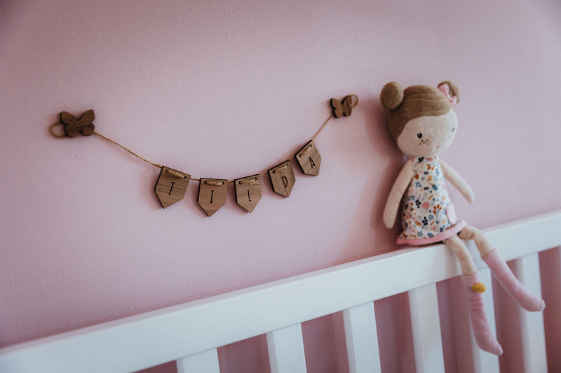 Minigirlande aus Holz auf einer pinken Wand im Kinderzimmer