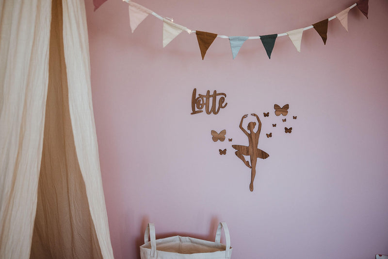 Namensschild aus Holz "Lotte" auf einer pinken Wand im Mädchenzimmer