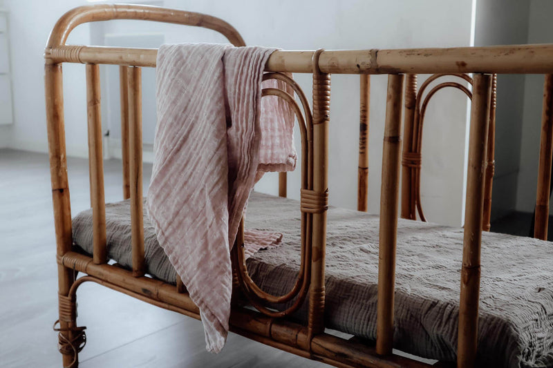 Ein Musselintuch hängend auf einem Babybett