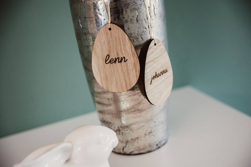 Zwei Ostereier aus Holz mit den Namen Lenn und Johanna hängend auf einer Vase