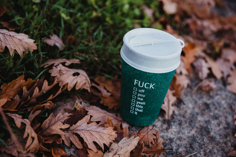 Fuck Kaffeebecher auf dem Boden mit Blättern